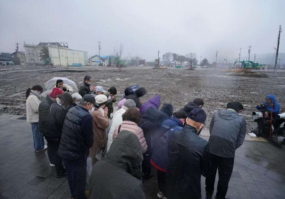 雨が強まる中、朝市通り周辺で黙禱をささげる輪島市朝市組合の関係者ら＝1日午後4時10分、石川県輪島市河井町（恵守乾撮影）