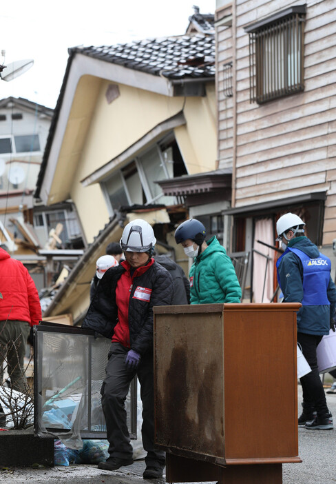 能登半島地震で、道路に散乱した災害ごみを片付けるボランティア＝２０２４年２月１０日、石川県輪島市