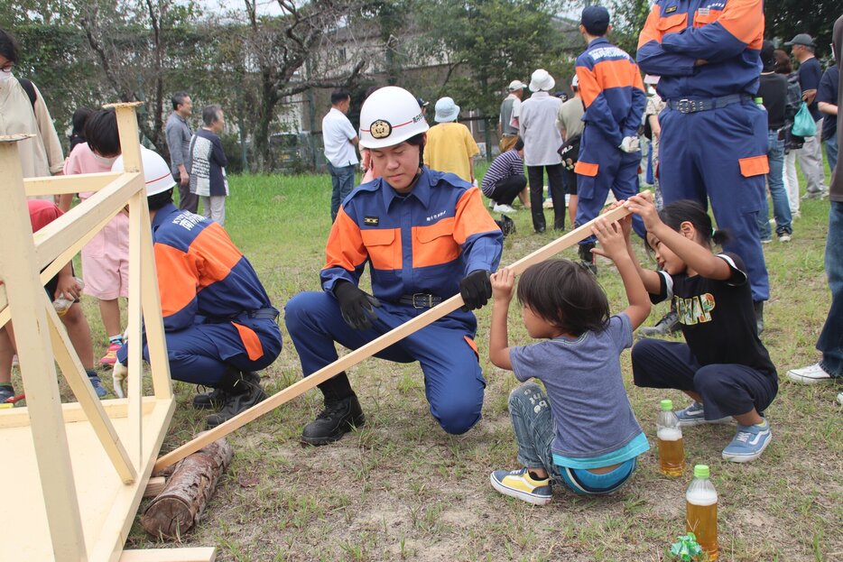 がれきを動かす方法を子どもたちに訓練で教える防災服姿の団員は、明治国際医療大の学生だった（２０２４年９月・京都府南丹市八木町）