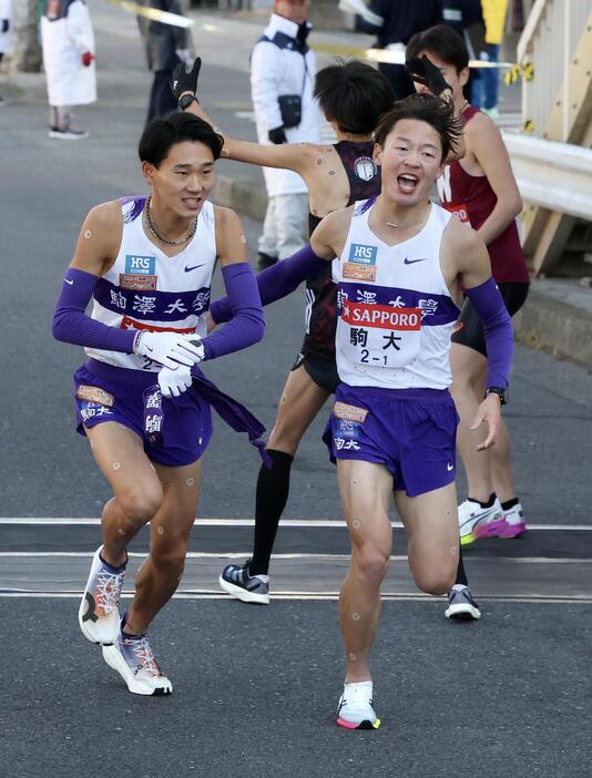 鶴見中継所を2位でタスキリレーする駒大1区帰山（右）と2区篠原（撮影・河田真司）