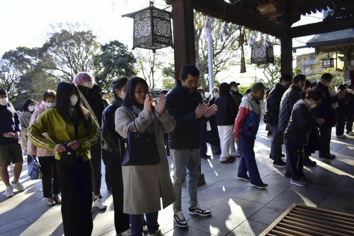 椿神社を参拝し、手を合わせる人たち＝1日午前、松山市居相2丁目