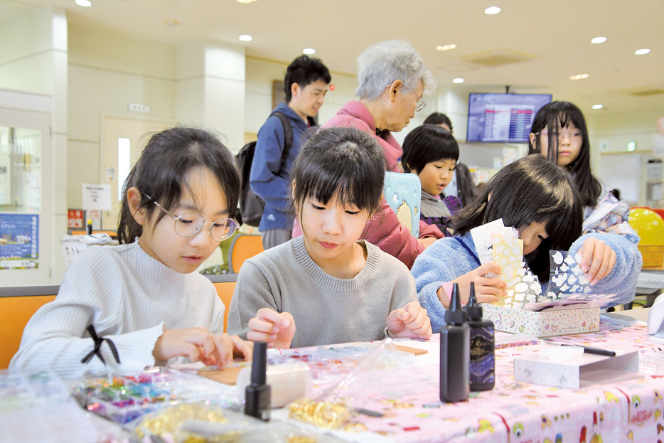 ワークショップブースで小物づくりに熱中する子どもたち＝3日、鹿児島県奄美市名瀬のAⅰAⅰひろば