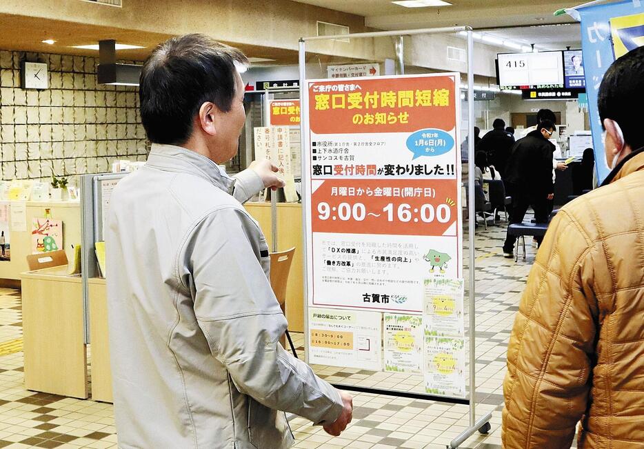 午後4時を過ぎて訪れた市民に案内板を見せる市職員（左）