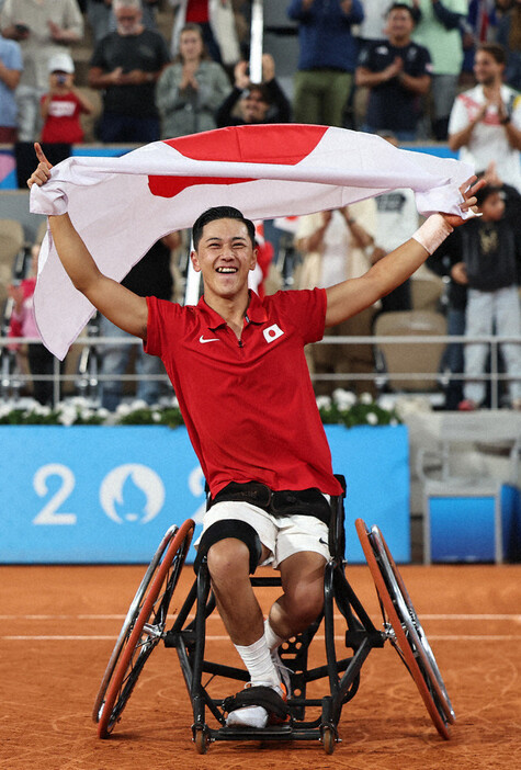 車いすテニス男子シングルス決勝を制し、日の丸を掲げる小田凱人選手＝ローランギャロスで２０２４年９月７日、玉城達郎撮影