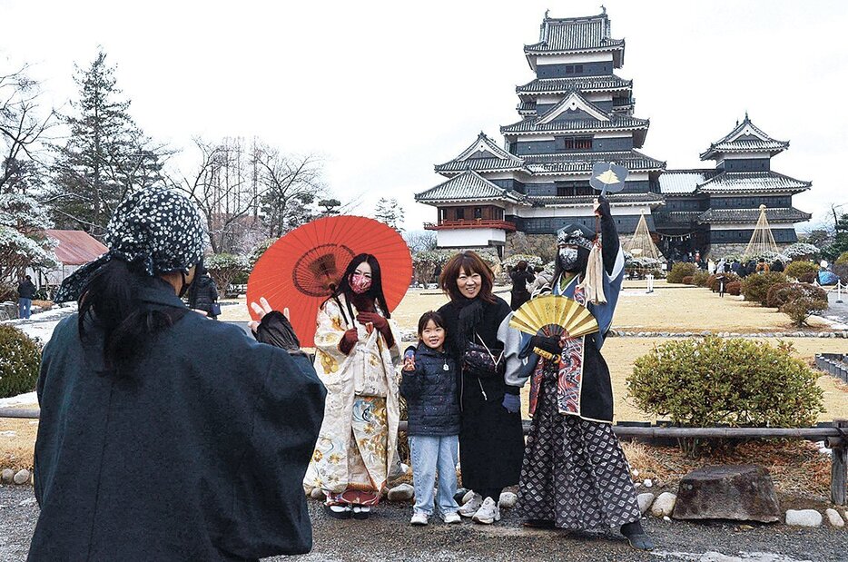 観光客らでにぎわう松本城。国宝松本城おもてなし隊と記念撮影をする家族連れの姿もあった（3日）