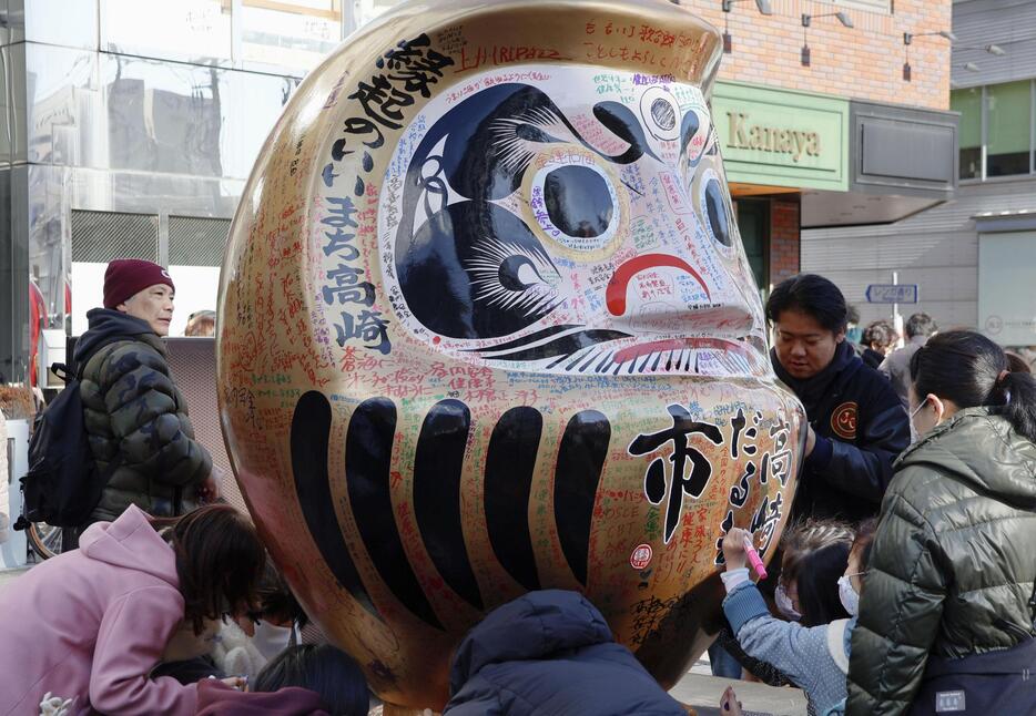 「高崎だるま市」でだるまに願い事を書き込む来場者＝1日午前、群馬県高崎市