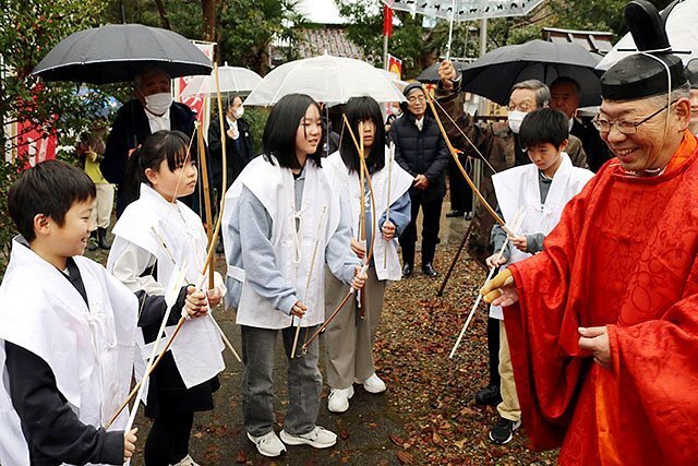 鈴木宮司（右）から弓と矢を受け取る地元児童