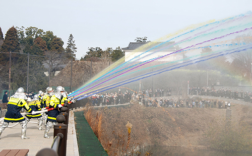 【一斉放水で新年を祝う消防団員ら＝亀山市本丸町の池の川で】