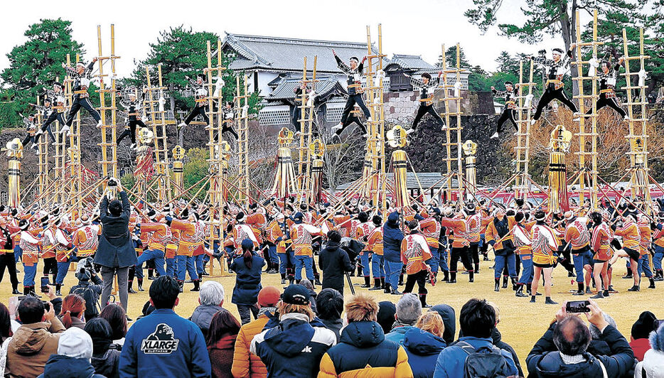 加賀鳶梯子登りで技を決める消防団員＝金沢城公園新丸広場