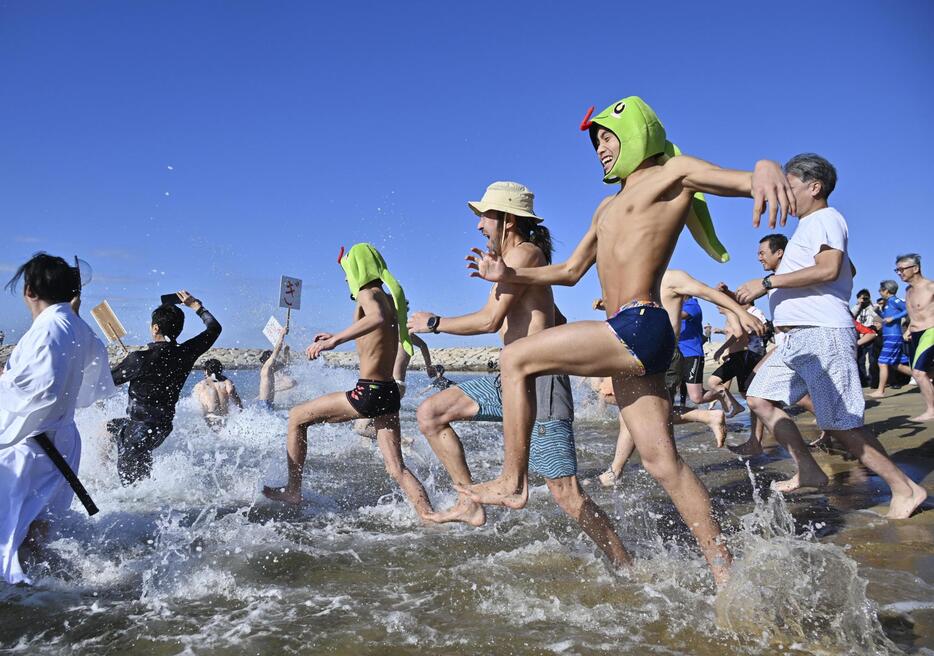 扇ケ浜海水浴場で開催された新春初泳ぎで、勢いよく海へ入る参加者たち＝2日午前、和歌山県田辺市