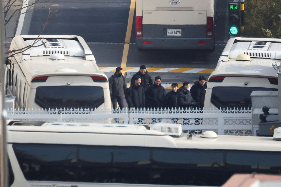 　１月８日、韓国の尹錫悦大統領に対する拘束令状を裁判所が再発布したことを受け、尹氏の弁護団は、令状は誤った管轄の裁判所から出されたもので、高官犯罪捜査庁（高捜庁）には現職の大統領を捜査する権限がないとして、令状失効は受け入れられないと述べた。写真は、ソウルの公邸で尹錫悦大統領を2度目の逮捕から守るために駐車されたバスの近くを歩く警備員。８日撮影（２０２５年　ロイター/Kim Hong-Ji）