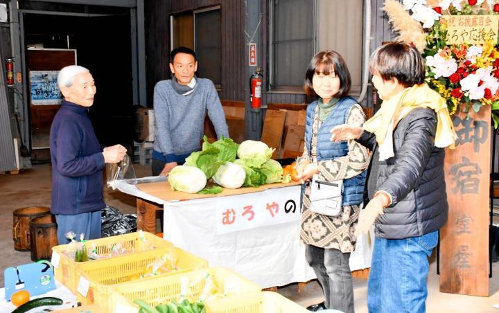 見学会に合わせ裏の畑で収穫した野菜を販売する室岡ヤス子さん（左）と太郎さん（左から2人目）親子