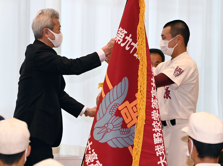 曽野校長（左）からセンバツ旗を受け取る福大大濠の川本主将＝徳野仁子撮影