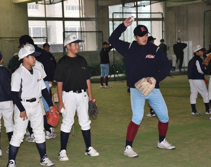 富山県氷見市内の学童野球チームの小学生に投球のコツを教える氷見のエース・青野拓海投手（右）＝氷見市の県立氷見高校で2022年12月17日、円谷美晶撮影