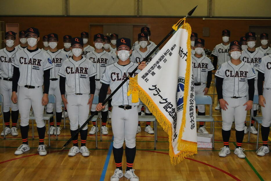 センバツ旗を手にするクラーク記念国際の白取主将（中央）と選手たち＝北海道深川市で２０２２年２月２８日、三沢邦彦撮影