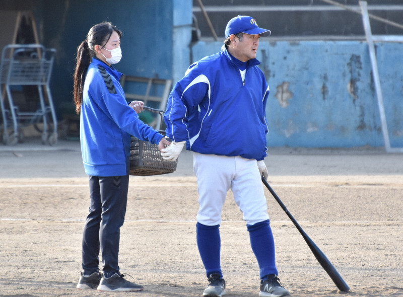 ノックをする明秀日立の金沢成奉監督（右）にボールを渡す田中杏璃副主将＝茨城県日立市で2022年3月7日午後4時5分、長屋美乃里撮影