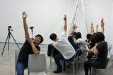 ACACで滞在制作した潘逸舟さん（左）の作品「揺れる垂直」の制作中の様子。市民と一緒に挙手して自然に揺れる腕の映像を撮影。風で揺れる木々の映像と対比させた＝2017年、ACAC提供