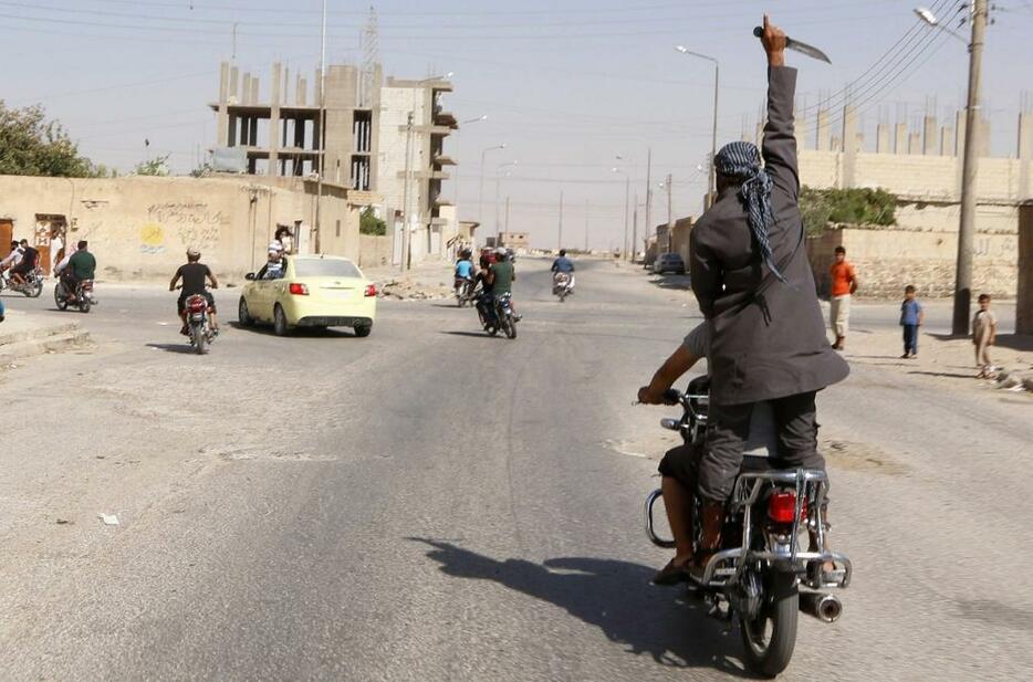 [写真]シリア内戦で「イスラム国」が空港を制圧。その後、バイクに乗ってナイフを掲げる兵士（ロイター/アフロ、2014年8月24日撮影）