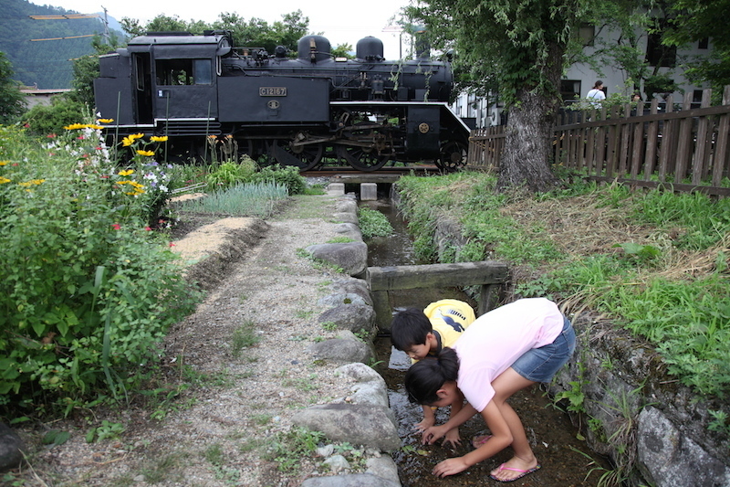 [写真]沿線でカニを見つける子どもたちの後ろをC12が走る（林義明氏撮影）