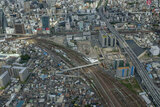 続けて広角レンズで名古屋駅南側を捉える。眼下には米野駅。中央付近に見えるのはあおなみ線のささじまライブ駅。上方を名鉄の電車が通り過ぎていく（2014年8月5日、吉永陽一撮影）。