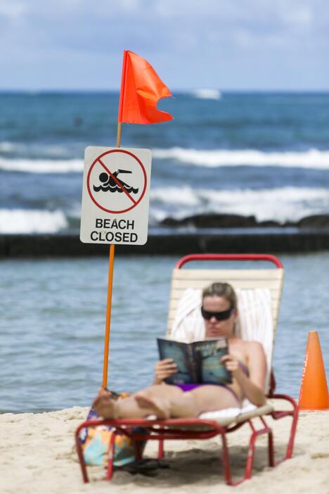 看板を背に読書する女性＝2015年8月25日（写真：ロイター/アフロ）