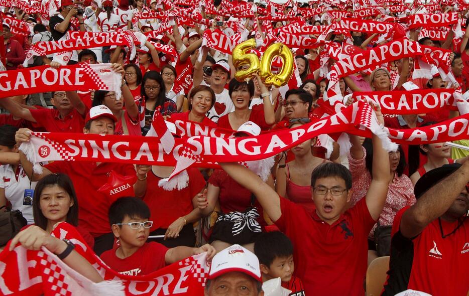シンガポールの旗を掲げる参加者＝2015年8月9日（写真：ロイター/アフロ）