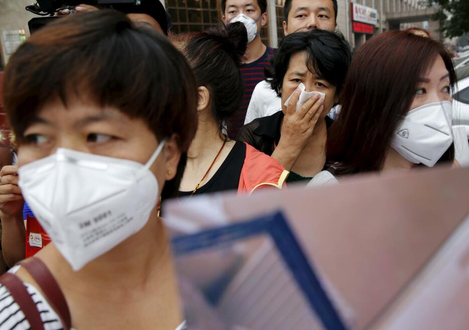 マスクをつけ、中国政府に補償を求める避難住民ら＝2015年8月18日（写真：ロイター/アフロ）