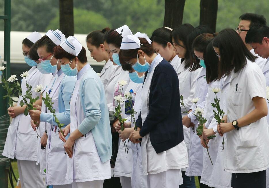 花を手に黙とうをささげる看護師ら＝2015年8月18日（写真：ロイター/アフロ）