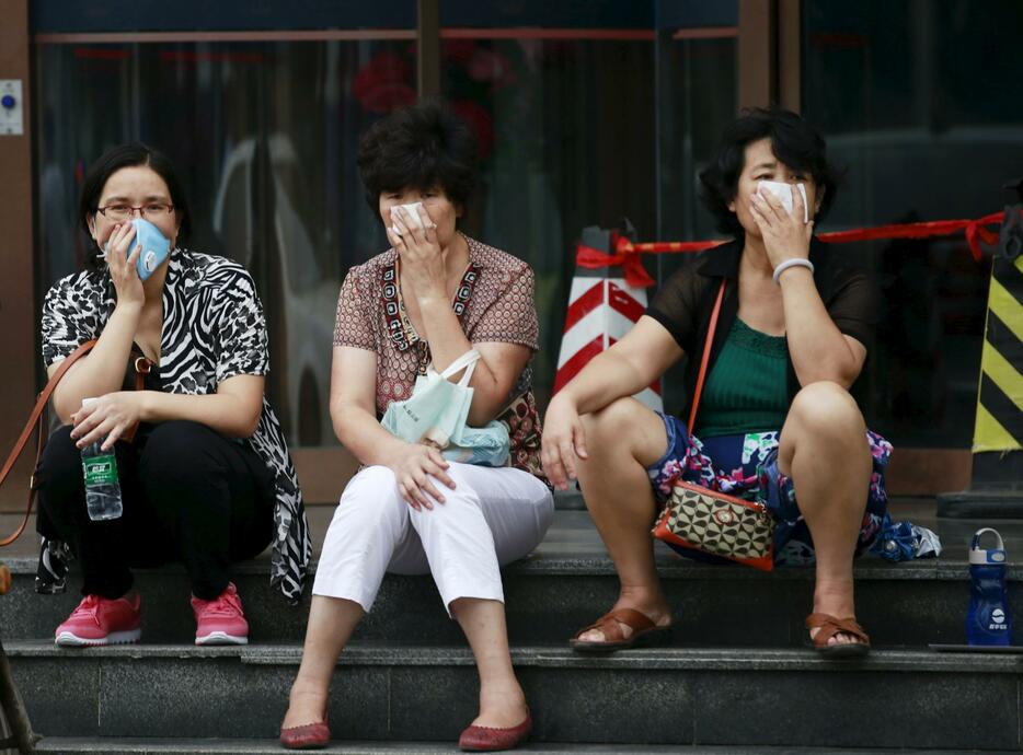 記者会見場の外に座り込む避難住民ら＝2015年8月18日（写真：ロイター/アフロ）