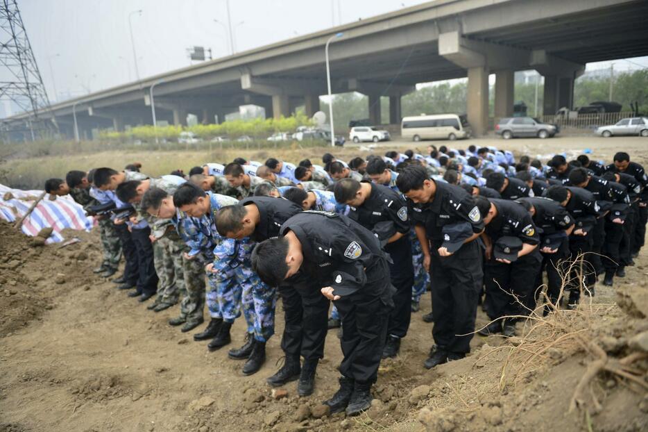 頭を下げる警官や人民解放軍の代表ら＝2015年8月18日（写真：ロイター/アフロ）