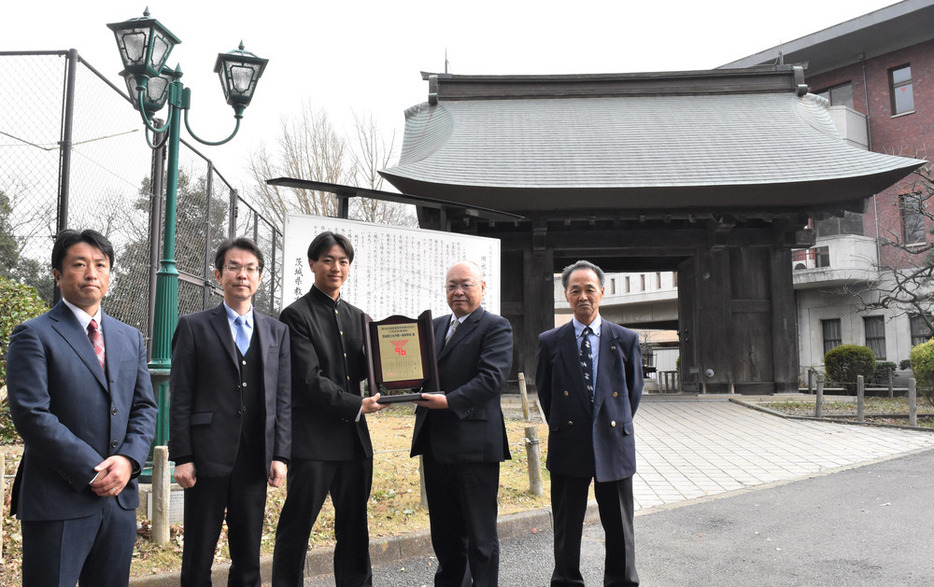 薬医門とガス灯の前で県高野連の深谷靖会長（右から２人目）から盾を受け取る津田誠宗主将（同３人目）＝水戸市三の丸３で２０２３年１２月１９日、川島一輝撮影