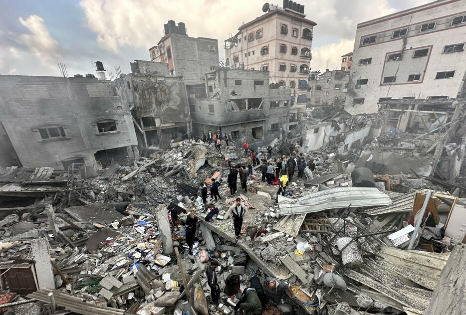 イスラエル軍の攻撃により崩壊した建物跡で救助活動をする民間防衛チームのメンバーら＝6日、パレスチナ自治区ガザ北部ジャバリヤ（ゲッティ＝共同）