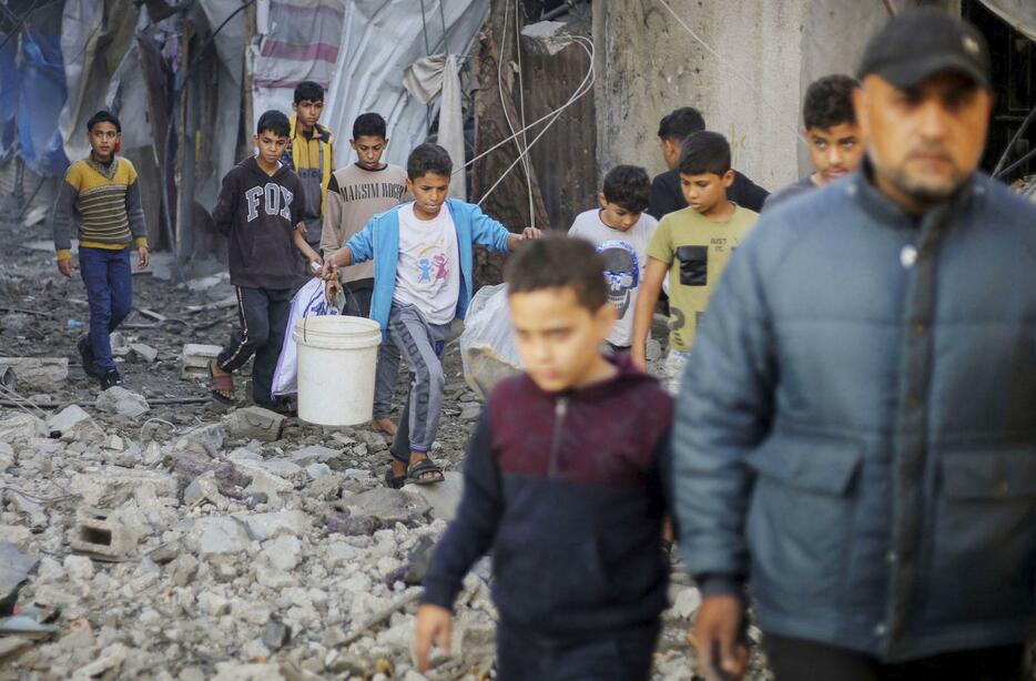 6日、パレスチナ自治区ガザ南部ハンユニスでイスラエル軍の空爆を受け、がれきが散乱する現場を歩く子どもら＝（ロイター＝共同）