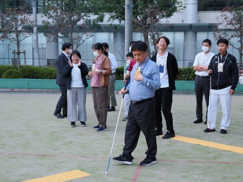 文京盲学校の校庭でアイナビの使い方を実演する川田さん＝１０月１２日