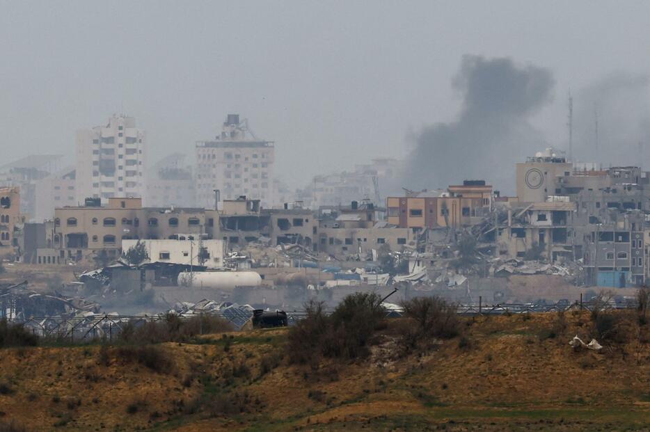 21日、パレスチナ自治区ガザで破壊された建物から上がる煙。イスラエル南部から撮影（ロイター＝共同）