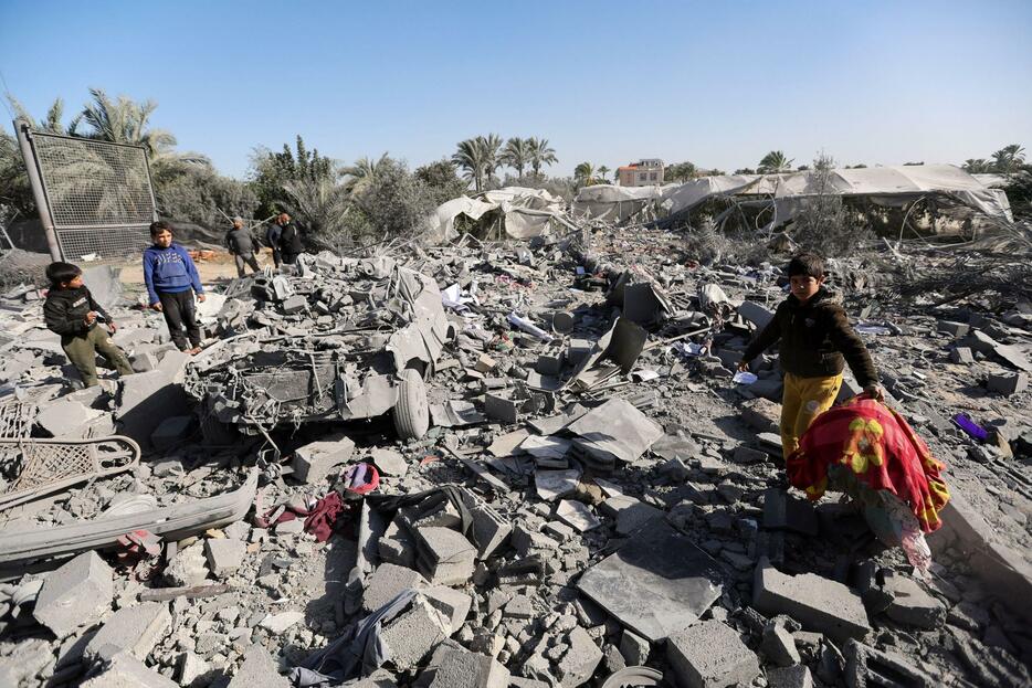 22日、パレスチナ自治区ガザ南部ラファで、イスラエル軍の空爆を受けた場所を調べる人々（ロイター＝共同）