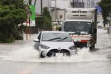 大雨の影響で冠水した道路を走る車（2023年7月福岡県久留米市）／（Ｃ）共同通信社