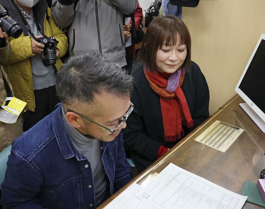 浜松市役所で性別変更が反映された書類を受け取る鈴木げんさん。右はパートナーの国井良子さん＝7日午前
