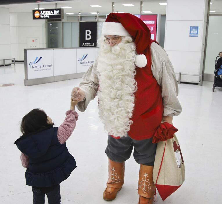 フィンランドから成田空港に到着し、子どもと握手するサンタクロース＝1日午後