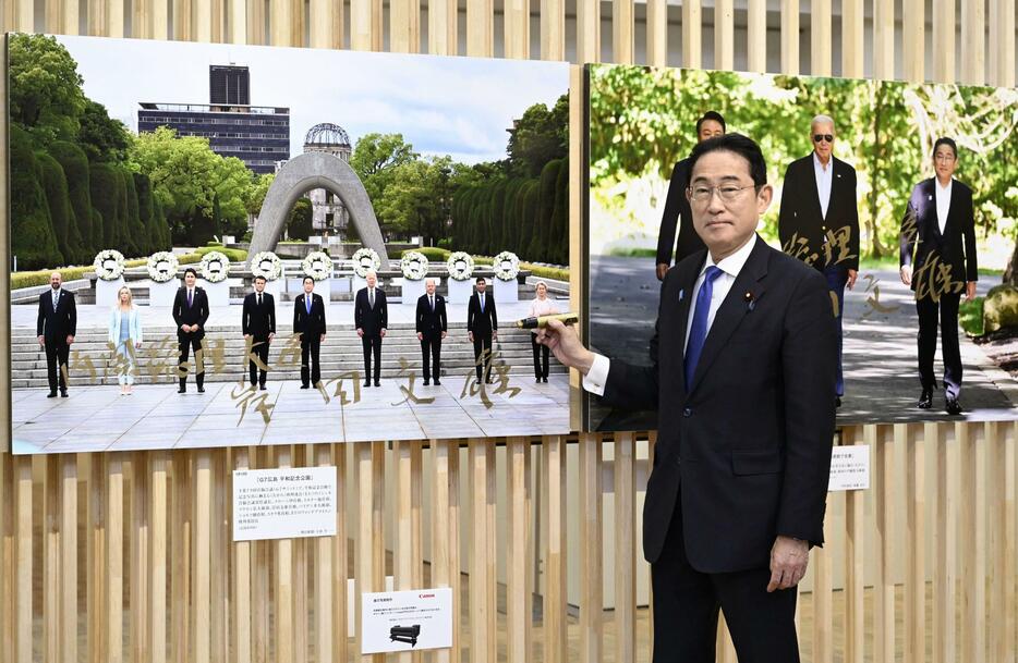 「2023年報道写真展」を訪れ、G7広島サミットの写真（左）などにサインした岸田首相＝20日午前、東京都中央区の日本橋三越本店