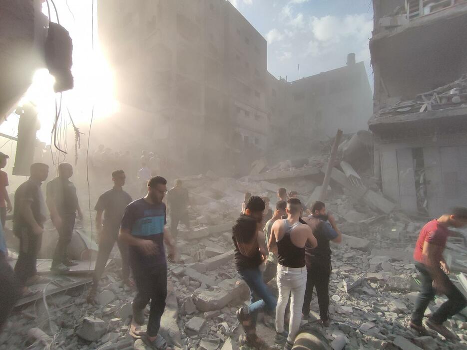 イスラエル軍の攻撃で破壊された建物のがれきが散乱する中、不明者を捜索する人々＝29日、パレスチナ自治区ガザ（ゲッティ＝共同）