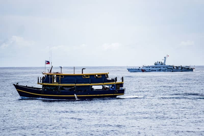 １１月１０日、南シナ海・アユンギン礁のフィリピン軍拠点への任務を終えた補給船（手前左）と中国海警局の艦船（右）（共同）