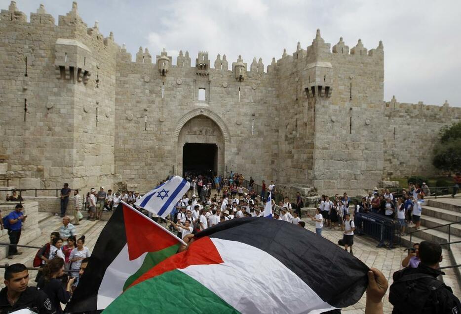 [写真]イスラエルが第三次中東戦争でエルサレム全域を制圧したことを記念するイスラエルの「エルサレムデー」。旧市街のダマスカス門の前でイスラエルとパレスチナの旗を振る人が見える（ロイター/アフロ）