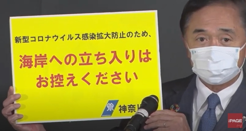 会見で、県内の海岸に設置する看板を掲げる黒岩知事