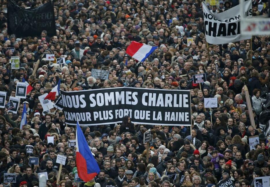 [写真]フランス紙襲撃テロ事件を受け、1月11日にパリで行われた大規模追悼デモ。「私たちはシャルリ」と書かれた横断幕を掲げている（ロイター/アフロ）