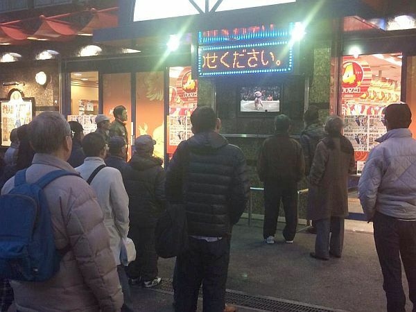 [写真]街頭テレビで相撲観戦を楽しむ人たち＝25日夕、大阪市都島区で