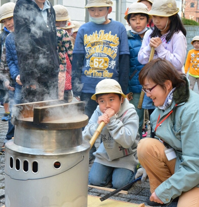 かまどの火おこしに挑戦する小学生（北区提供）