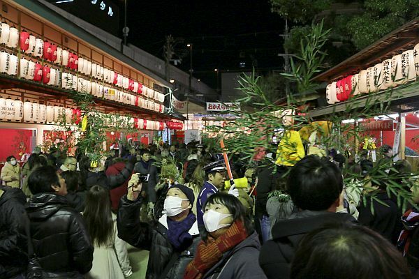 [写真]ササをかざして歩く人たち。残り福、ええ福もらいましたか？＝11日午後9時半ごろ、大阪市浪速区で