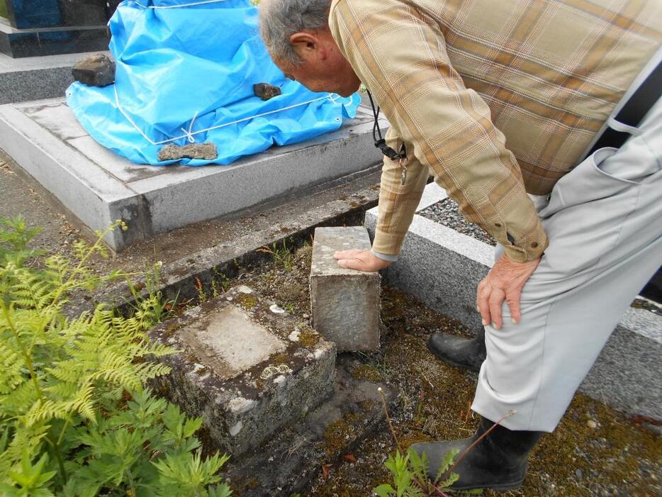 [写真]倒れた古い墓石などを整える男性（27日・栄村堺地区）