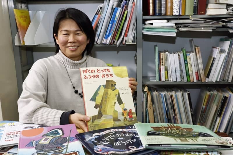 ロシアの絵本を扱う「かけはし出版」を立ち上げた藤原潤子さん。手にしているのは１作目に出版した「ぼくのとってもふつうのおうち」＝２月２１日、神戸市